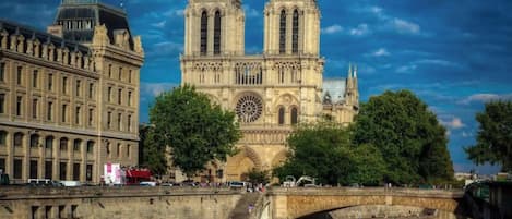 A historic cathedral with two prominent towers, a large rose window, and a river in the foreground.