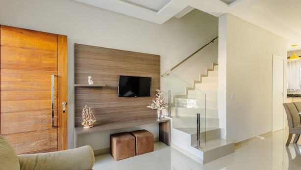 Een moderne woonkamer met een houten wandpaneel, een flatscreen televisie, een trap en een glazen balustrade.