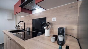 A modern kitchen with a wooden countertop, a black stove, and a coffee maker.