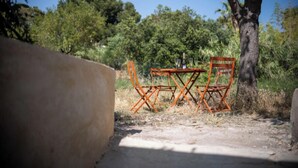 A table and chairs set outdoors with a tree and greenery in the background.