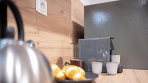 A kitchen counter with a kettle, a plate of croissants, and a coffee machine.