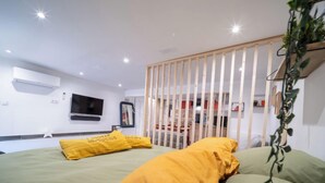 A modern bedroom with a bed, a TV, and a wooden partition.