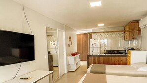 Ett hotellrum med TV, skrivbord, säng och ett litet kök.