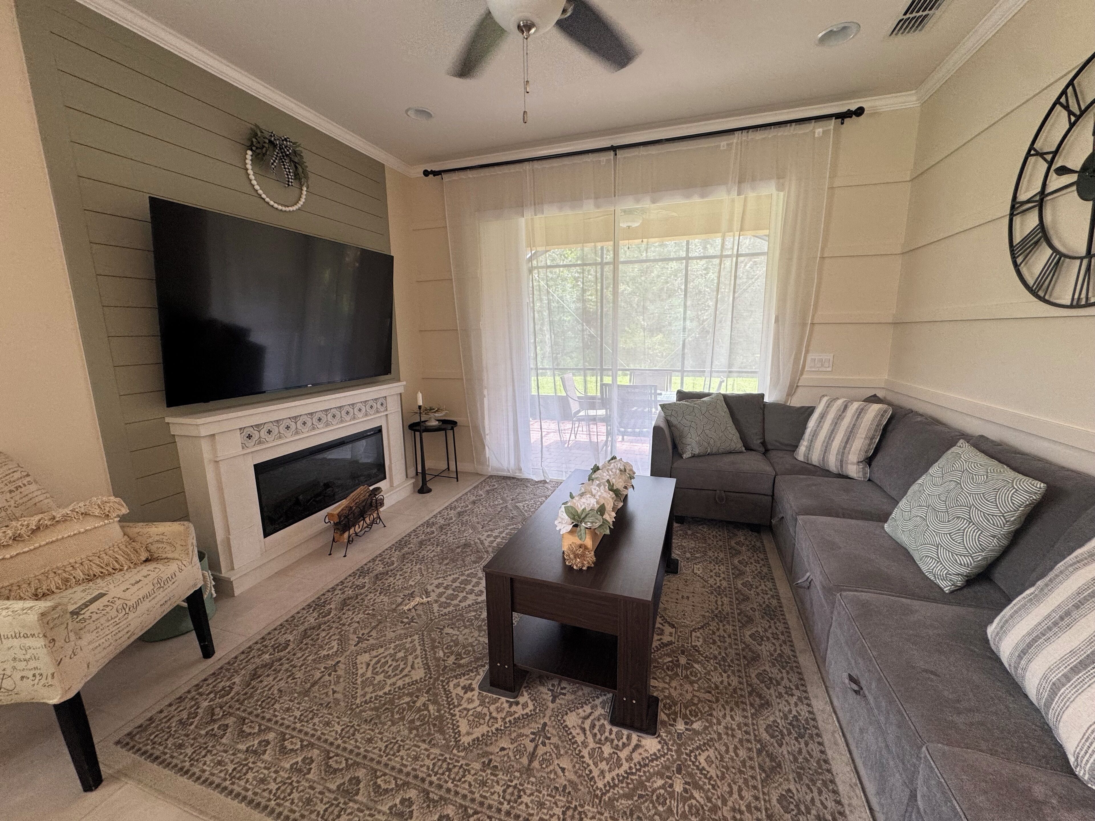 A living room with a fireplace, a large flat-screen TV, a sofa, and a coffee table.