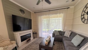 A living room with a fireplace, a large flat-screen TV, a sofa, and a coffee table.
