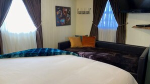 A hotel room with a large bed, a smaller bed, and a TV on the wall.