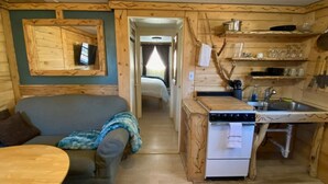 A compact cabin-style room with a kitchenette, a sofa, and a small dining table.