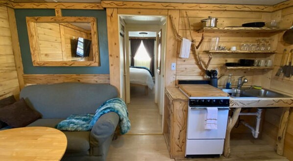 A compact cabin-style room with a kitchenette, a sofa, and a small dining table.