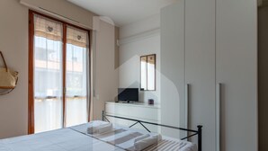 A hotel room with a bed, a TV, a desk, and a wardrobe. - Homiday - Lungomare dei Pini, D2 (Pineto)