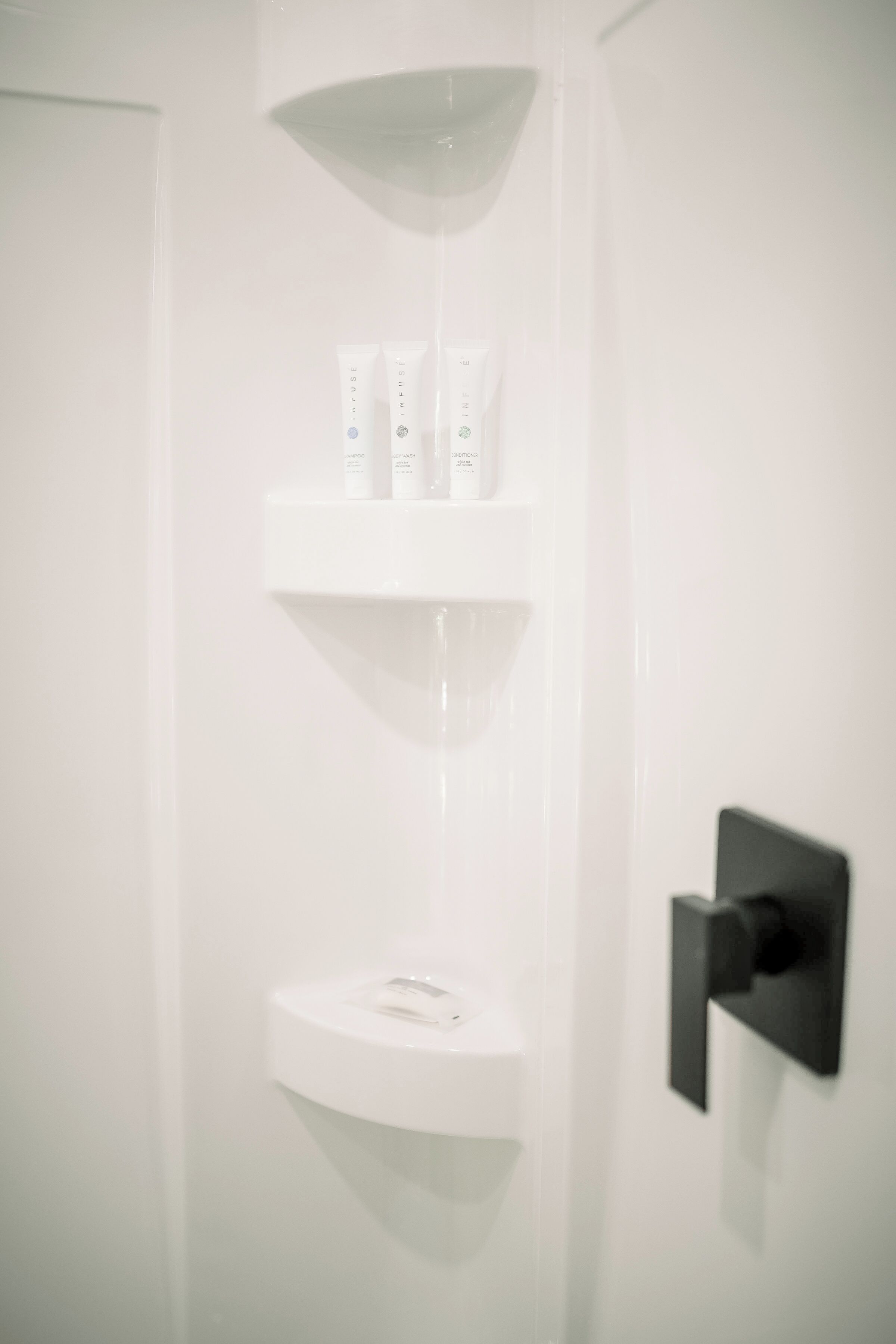Une salle de bain avec un lavabo blanc, un miroir et une étagère contenant des articles de toilette.