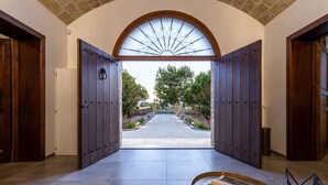A hallway with a large arched window, wooden doors, and a view of a garden.