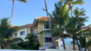 A two-story building with a tiled roof, surrounded by palm trees.