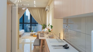 A modern kitchen with a dining area, large windows, and a view of the city. - Majestic Residence KL by The Stay Hub  (Kuala Lumpur)
