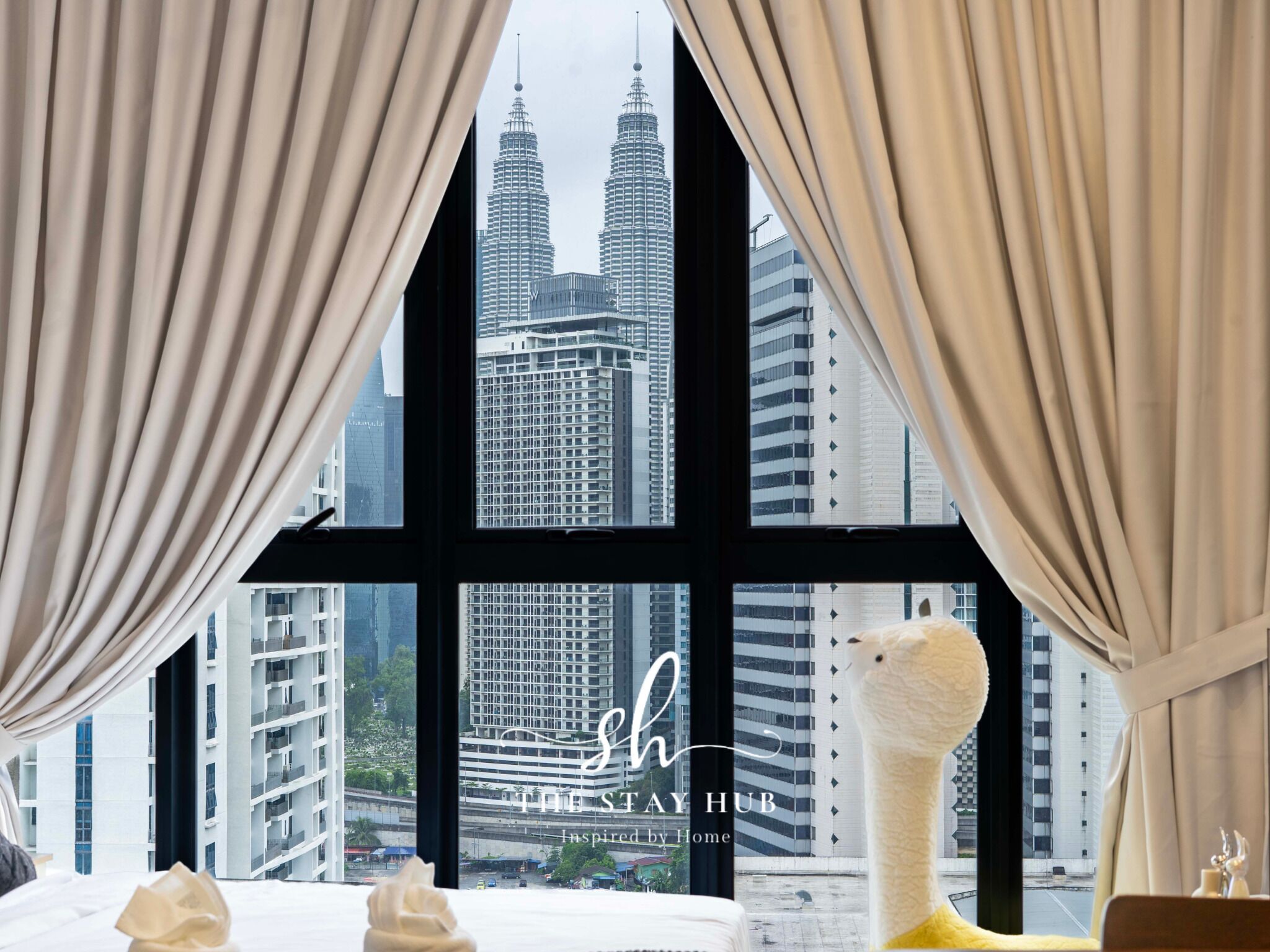 Habitación de hotel con vistas a las Torres Petronas, un ventanal grande y una escultura decorativa en el alféizar.