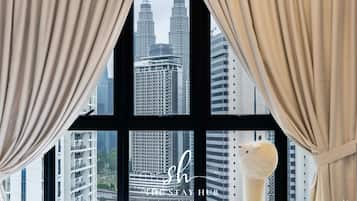 Habitación de hotel con vistas a las Torres Petronas, un ventanal grande y una escultura decorativa en el alféizar.