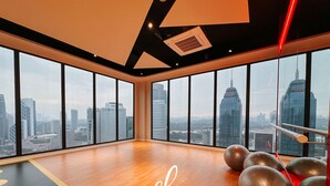 A spacious room with large windows offering a city view, exercise equipment, and a wooden floor. - Majestic Residence KL by The Stay Hub  (Kuala Lumpur)