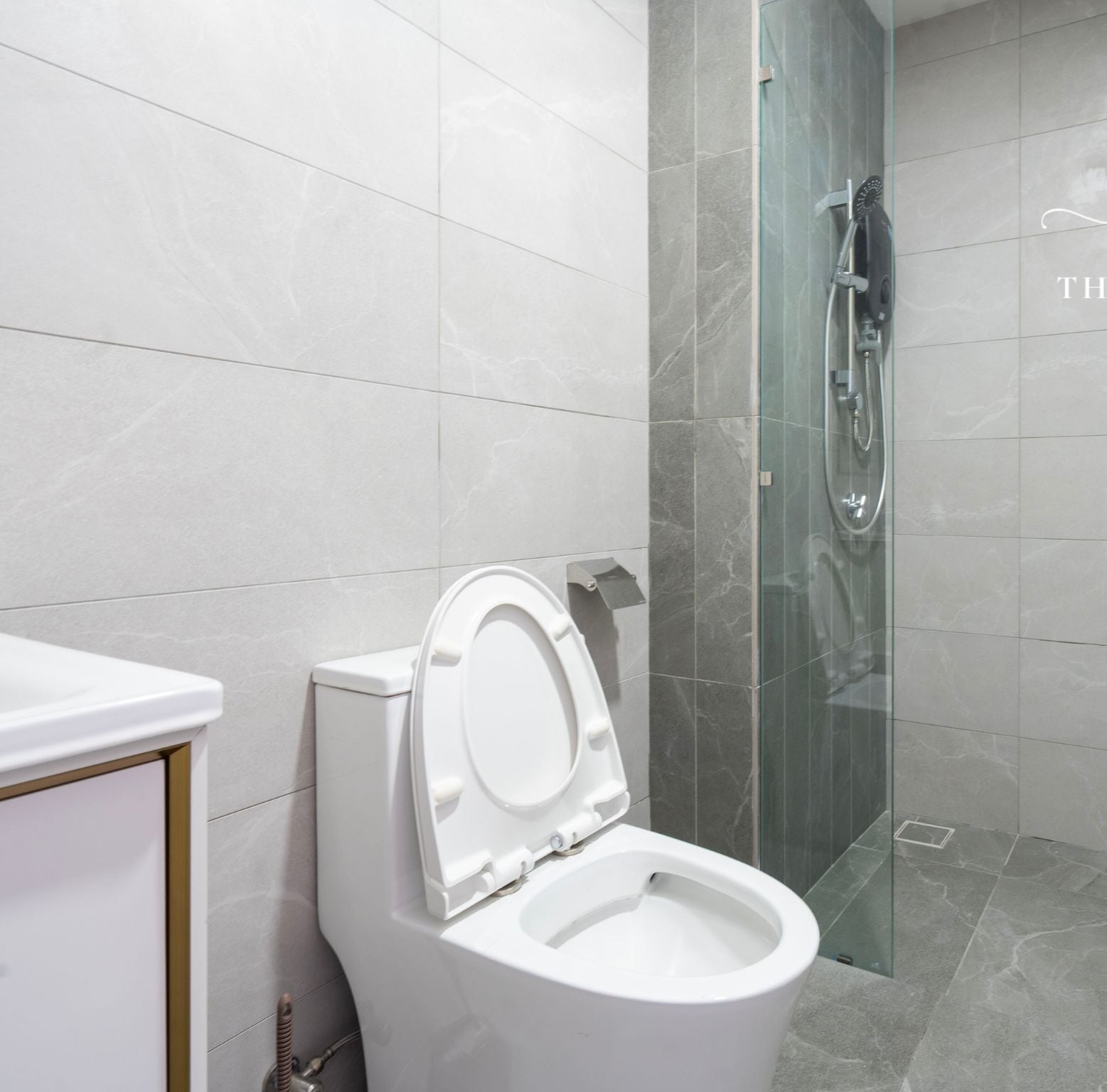 Un baño moderno con inodoro, cabina de ducha de vidrio y suelo de mármol.