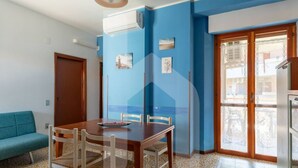 A dining area with a wooden table and chairs, a blue wall, and a patterned floor. - Homiday - Waterfront of the Pines, D1 (Pineto)