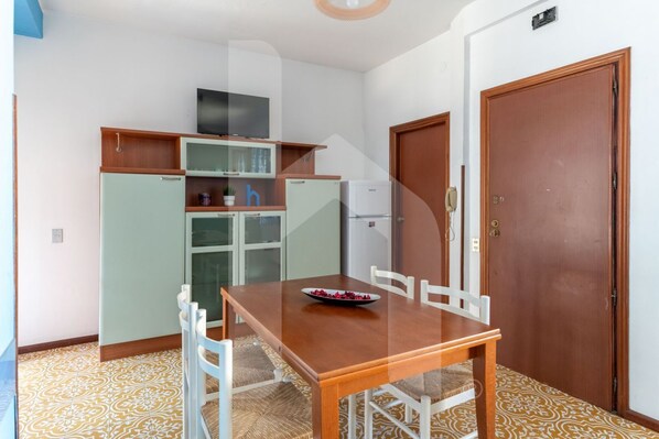 Una cocina compacta con una mesa de comedor, sillas y un refrigerador.