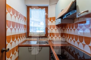 A compact kitchen with a sink, a small refrigerator, and a stove.