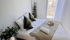 Une chambre à coucher moderne avec un lit, une table de chevet et une vue sur l’extérieur.