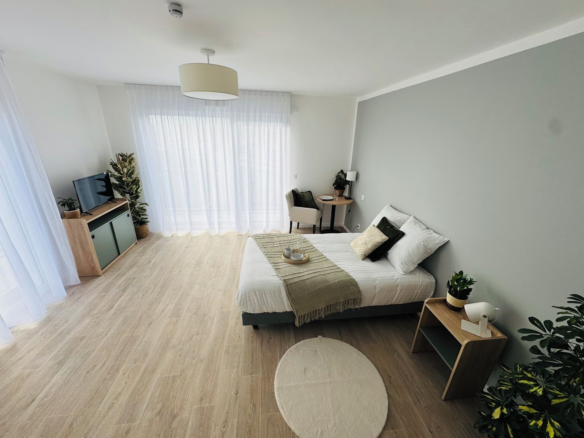 Un dormitorio moderno con cama, mesita de noche y escritorio con silla.