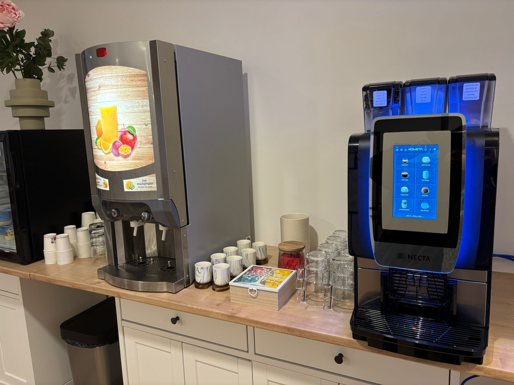 Eine Kaffeestation mit Saftspender, Kaffeemaschine, Tassen und einem kleinen Mülleimer.