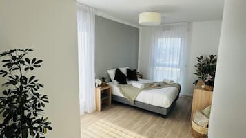 A modern bedroom with a bed, bedside tables, and a large potted plant.