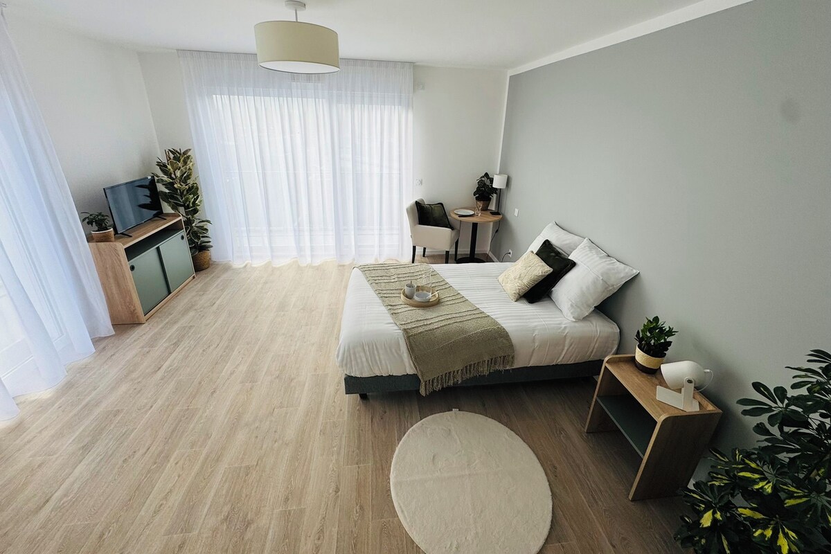 Een moderne slaapkamer met een bed, nachtkastje en bureau met stoel.