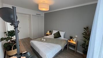 Een moderne slaapkamer met een bed, nachtkastjes, een lamp en potplanten.