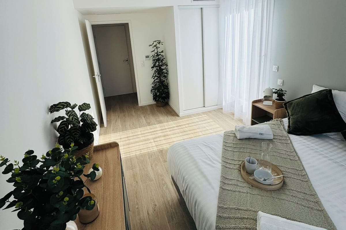 Een moderne hotelkamer met een bed, nachtkastje en een potplant.