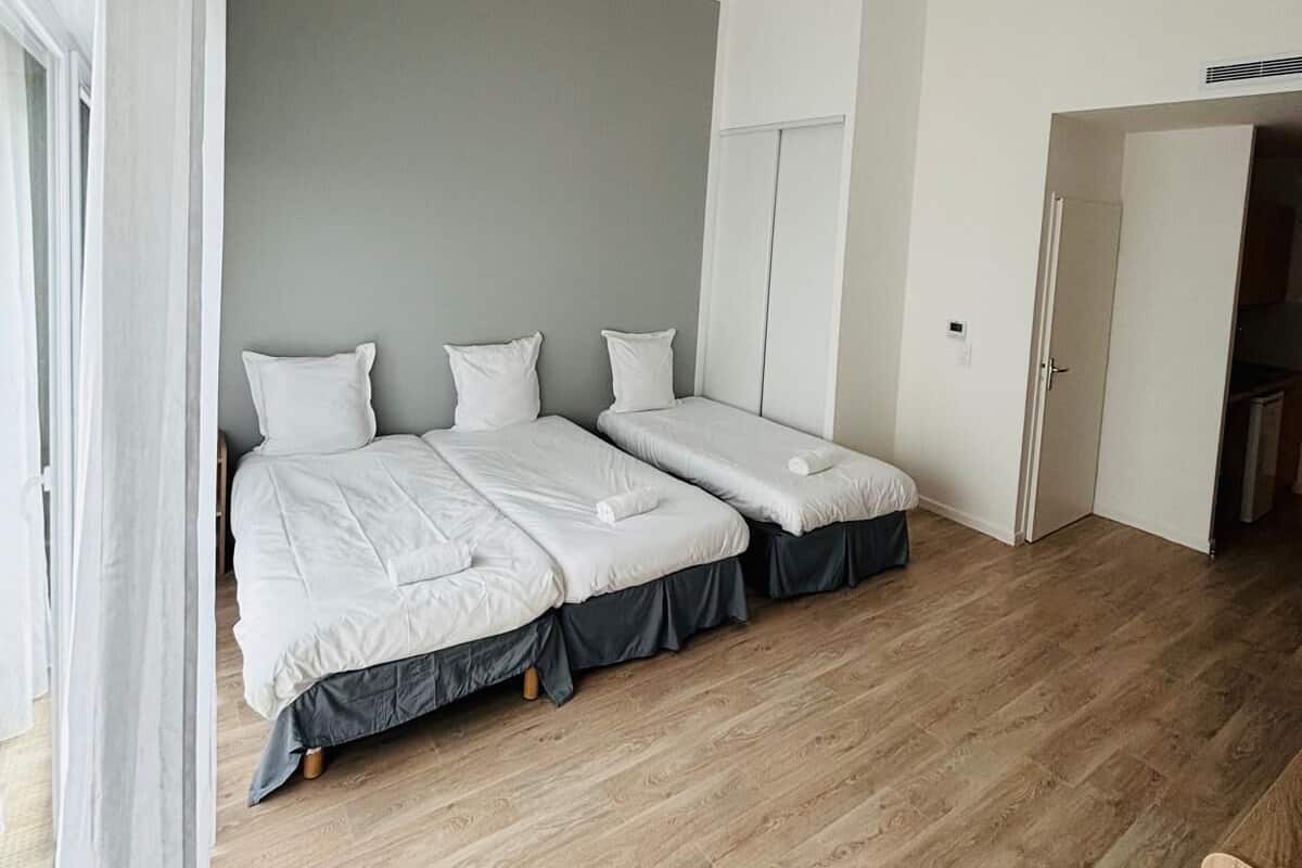 Een slaapkamer met twee bedden, een kledingkast en een deur naar een badkamer.