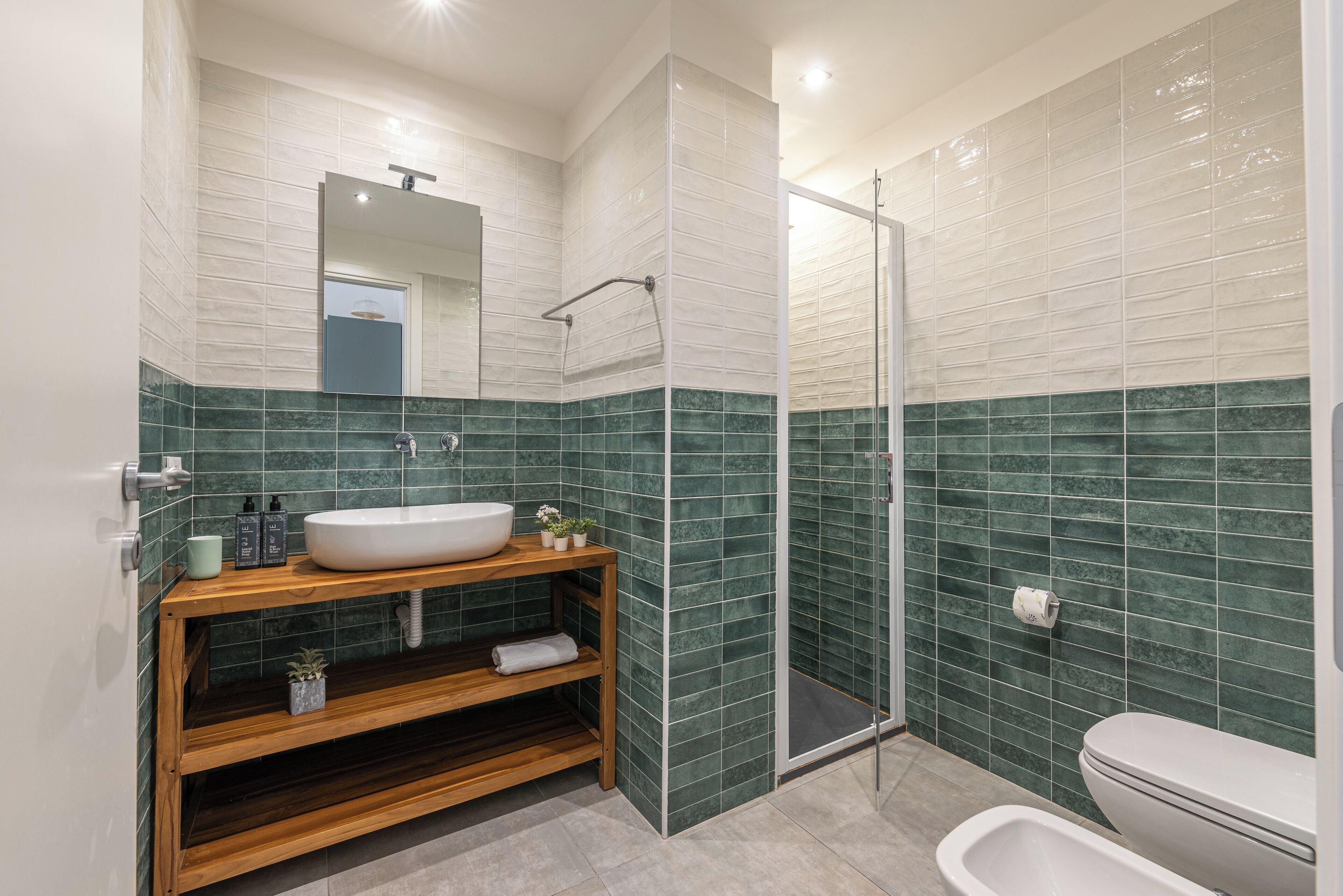 Une salle de bain moderne avec un lavabo sur pied, une douche à parois de verre et des toilettes.