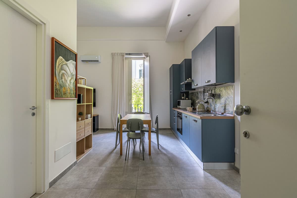 A modern kitchen with a dining area, featuring a table and chairs, a built-in oven, and a microwave.