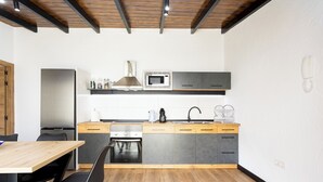A modern kitchen with a wooden table, black chairs, a built-in oven, a microwave, and a sink.