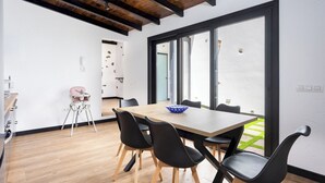 A modern dining area with a wooden table, black chairs, and a large window.