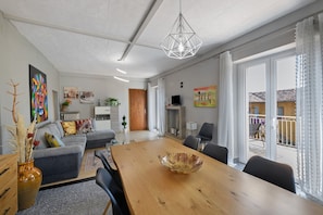 A modern living room with a dining table, sofa, and artwork. - 'Isola Bella' Apartment with Mountain View, Private Terrace and Wi-Fi (Sottocastello)