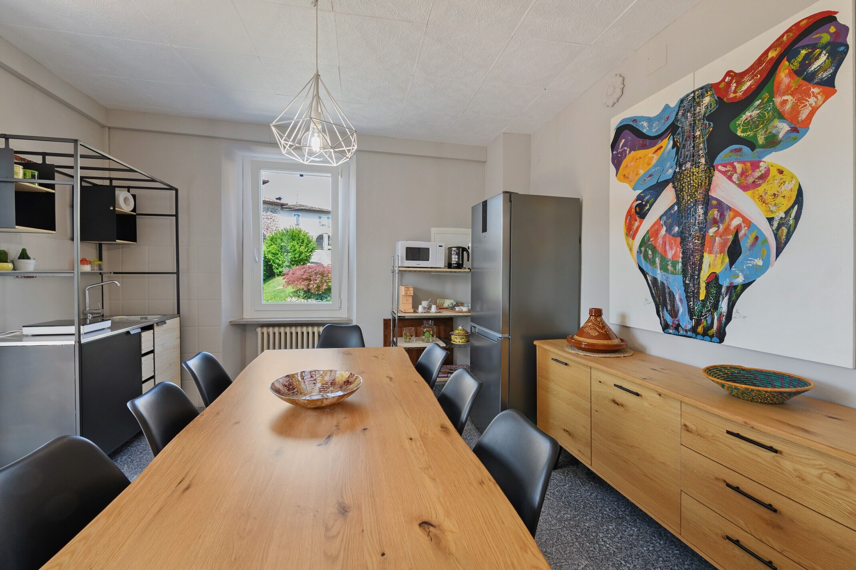 Una cocina moderna con comedor, un ventanal grande y un cuadro abstracto de colores.