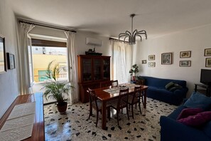 A dining area with a wooden table and chairs, a cabinet, and a blue sofa. - Walk hrough the streets of Alghero's historic center to reach Rachele's apartment. Immerse yourself in the charm of Sardinia, where traditional symbols and Catalan culture blend, still evident in the city's streets. Enjoy Sardinia's best beaches and savo (Alghero)