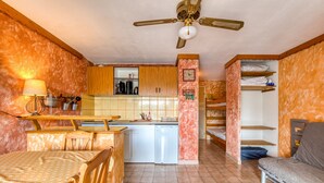 A compact living space with a kitchenette, a dining area, a bed, and a ceiling fan.