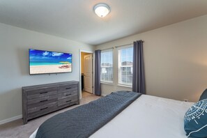 A bedroom with a bed, a dresser, a TV on the wall, and a window with curtains. - Discover Your Perfect Getaway 8BR Wonder (Davenport)