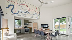 Un vaste espace de vie comprenant une table à manger, des chaises, un téléviseur et une grande carte accrochée au mur.