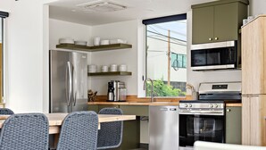 Une cuisine moderne équipée d’un réfrigérateur en acier inoxydable, d’une machine à café et d’un four encastré.