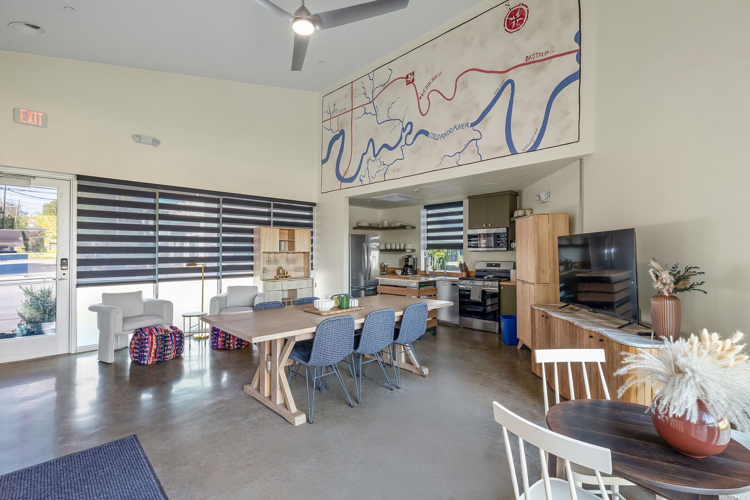 A modern kitchen with a dining area, a map on the wall, and a TV on the right.