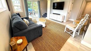 A modern living room with a sofa, coffee table, and TV. - Beautiful Lakehouse close to everything! (Huron)