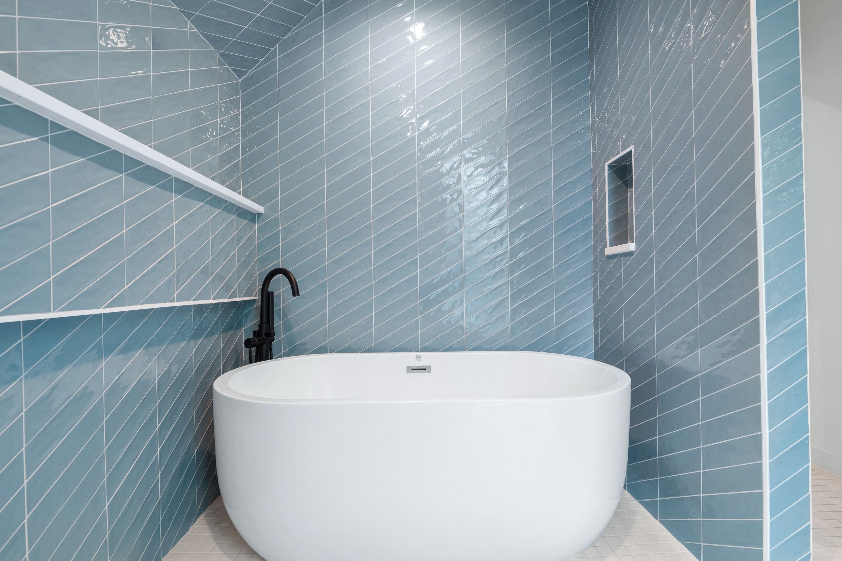 A modern bathroom with a freestanding bathtub, tiled walls, and a small window.