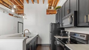 A modern kitchen with dark cabinets, stainless steel appliances, and a white countertop.