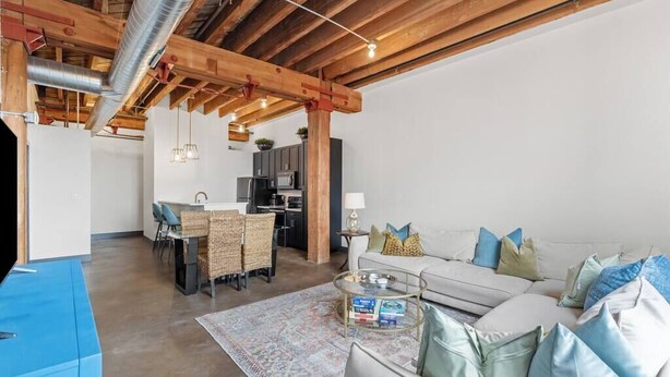 A modern living room with a sofa, coffee table, and a dining area with chairs and a table.