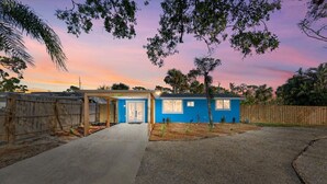 A single-story building with a blue exterior, a covered porch, and a clear sky at dusk. - Coastal 2-Bedroom Home Minutes to Beach (Englewood)