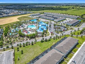 Vista aérea de un complejo turístico con varias edificaciones, un área de piscina y un estacionamiento.